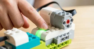 Тестовый режим смарт-хаба WeDo 2.0: палец нажимает зелёную кнопку, индикатор горит зелёным, к хабу подключён мотор
