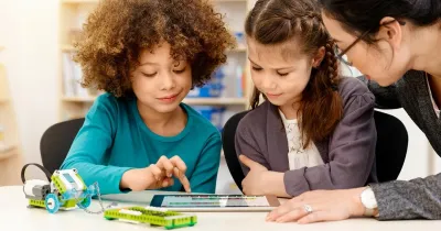 Ученики на занятии по робототехнике собирают модель WeDo 2.0 и работают с планшетом