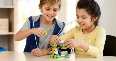 Двое детей собирают модель робота из набора WeDo 2.0 — сравнение робототехники и обычного конструктора