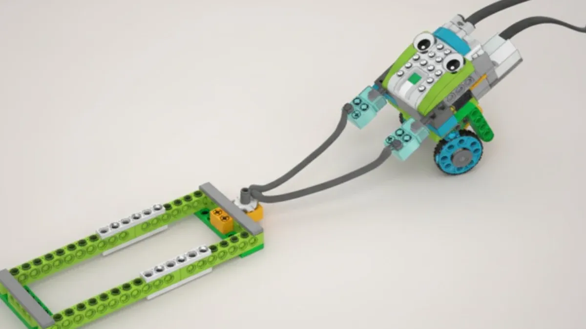 Тянущий робот из деталей, совместимых с WeDo 2.0: корпус с нарисованными глазами на двух голубых колёсах тянет за пару серых тросов плоскую раму из зелёных балок