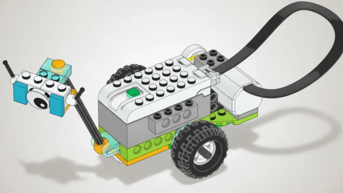 Вездеход Майло из деталей, совместимых с WeDo 2.0: белый СмартХаб с зелёной кнопкой на колёсной базе, впереди на наклонной штанге закреплён прибор с глазком и оранжевым куполом