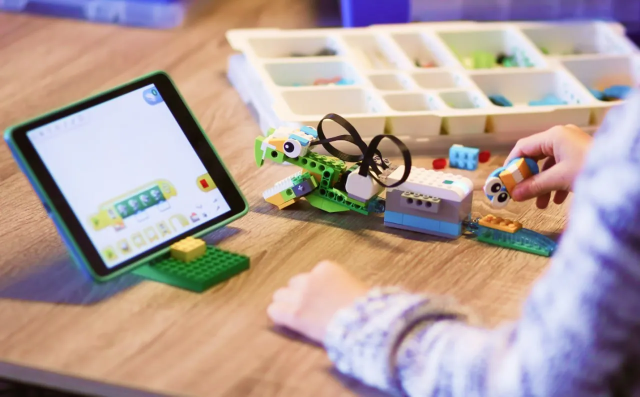 Ребёнок программирует собранного из конструктора РобоГуру (совместим с WeDo 2.0) робота в приложении на планшете