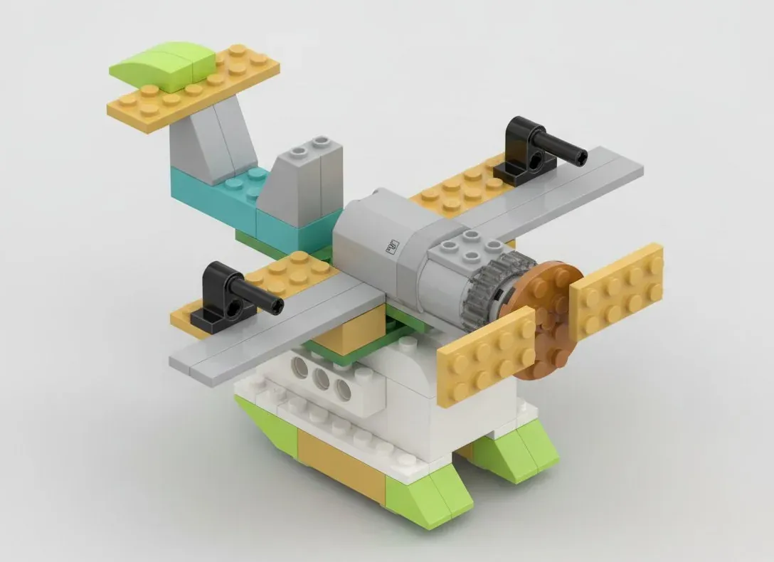 Самолёт с турбинами из деталей, совместимых с WeDo 2.0: серый цилиндр мотора вдоль фюзеляжа, на его оси винт с песочно-жёлтыми лопастями, на прямых серых крыльях по чёрной стойке-турбине, снизу бело-салатовые поплавки; датчик наклона утоплен в корпус и снаружи не виден
